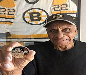Willie O'Ree Holding Commemorative Coin