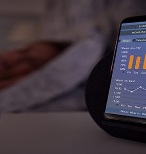 Woman Sleeping In Bed With Sleep Data App Running On Mobile Phone On Bedside
